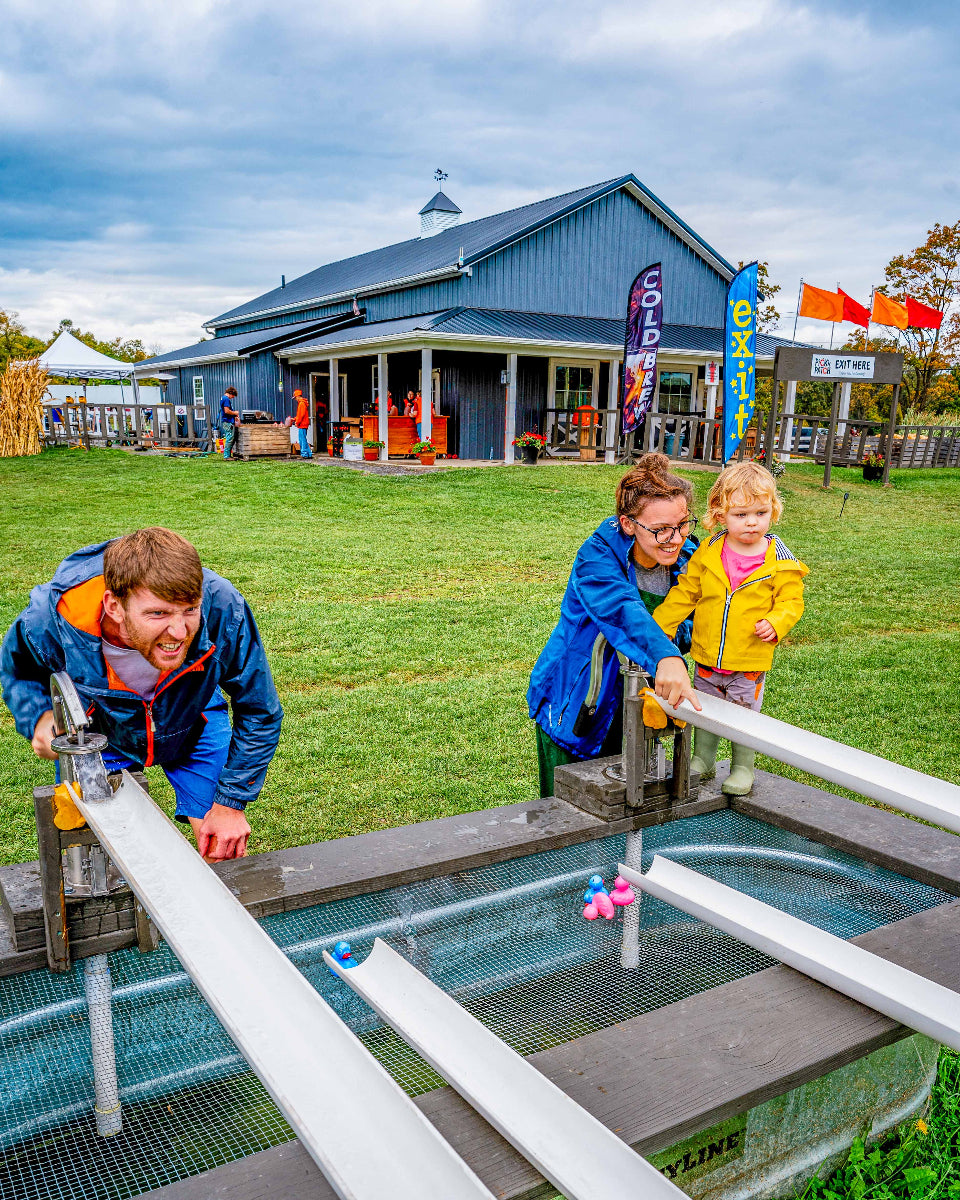 a family racing ducks on the water duck race with the farm market in the background