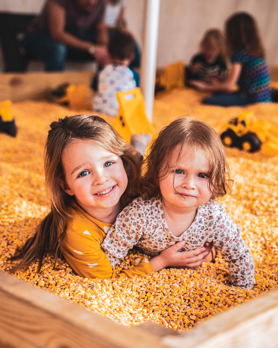 two young girls in the corn box